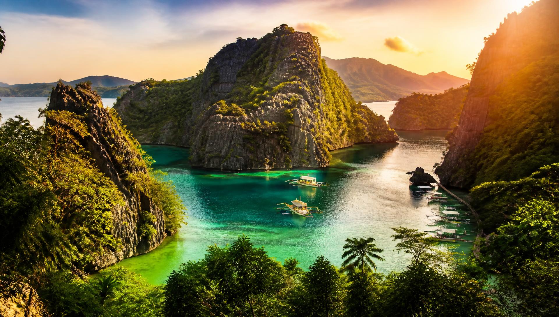 Turquoise lagoon framed by jungle-covered karst cliffs at sunset